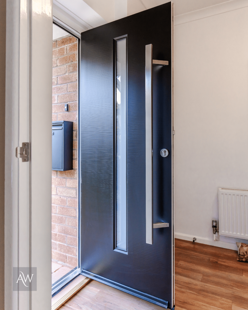 alexander windows installation of a rockdoor dune composite door in black. Photograph shows the external view of the door taken from inside the property with the door ajar.