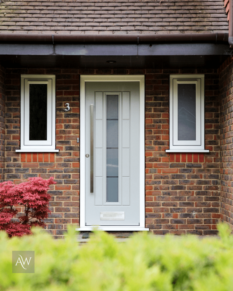 alexander windows installation of a Rockdoor Vermont in painswick with white frame, long bar handle and letter plate. This photograph shows the door from the external view alongside two Kommerling flush casement windows (also installed by alexander windows)